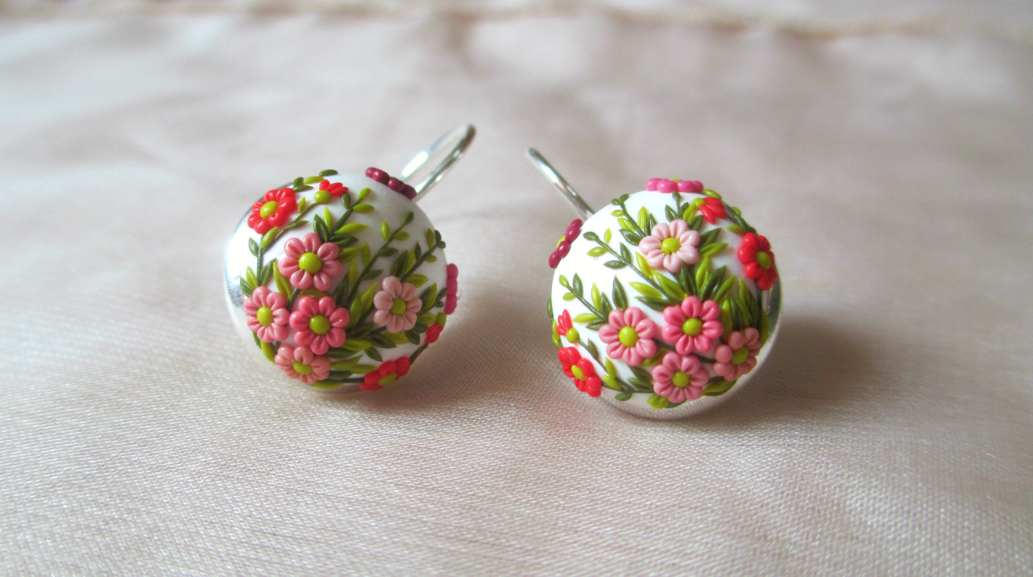 A close-up of handcrafted polymer clay earrings featuring a floral design clay technique